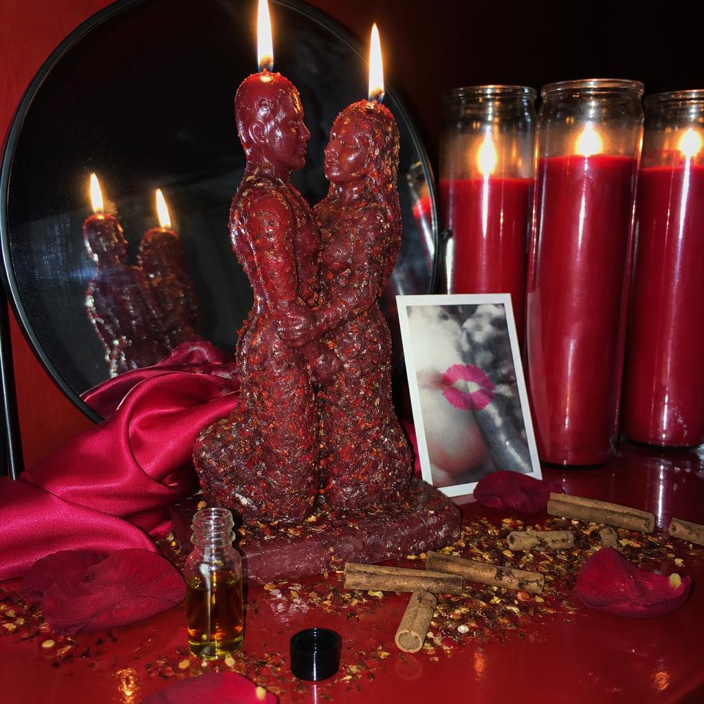 Passion rekindling love spell altar with red tapers, vigil candle, cinnamon, rose petals and handwritten petition.